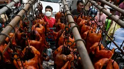 Pekerja menurunkan babi panggang di pasar menjelang Tahun Baru Imlek yang menyambut Tahun Macan di Phnom Penh, Kamboja, Senin (31/1/2022). Menyambut Tahun Baru Imlek, warga Kamboja mempersiapkan daging babi panggang untuk sajian makan. (AFP/Tang Chhin Sothy)