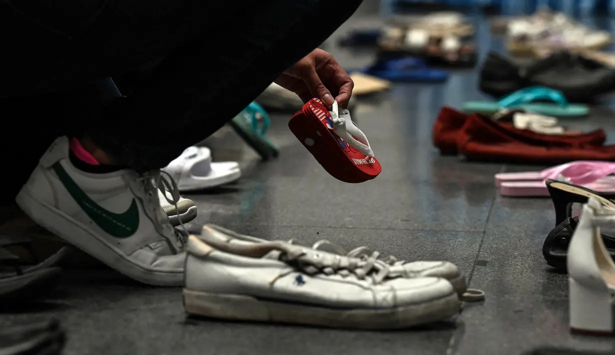 Seorang staf medis memegang sepasang sepatu, bagian dari instalasi seni dengan 321 pasang sepatu yang menandakan kematian yang disebabkan oleh merokok, dalam rangka memperingati Hari Tanpa Tembakau Sedunia di Pusat Paru Filipina, Quezon City, pinggiran kota Manila, Filipina, Selasa (31/5/2022). (JAM STA ROSA/AFP)
