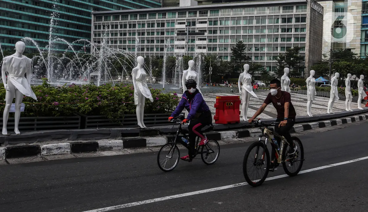 Pesepeda melintasi puluhan boneka maneken yang dipajang di Bundaran HI, Jakarta, Minggu (15/11/2020). Boneka maneken itu sebagai bentuk "Mengenang Korban Kecelakaan Lalu Lintas 2020" dan mengingatkan pengguna jalan agar selalu patuhi peraturan lalu lintas demi keselamatan. (Liputan6.com/Johan Tallo)