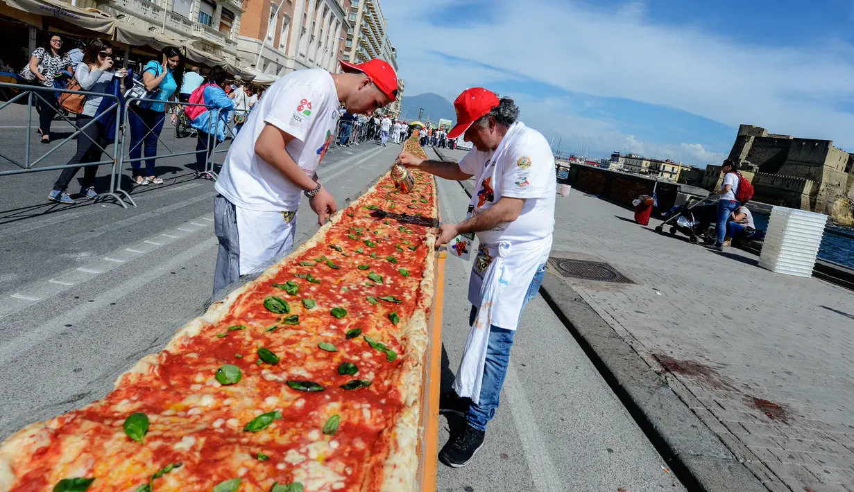 Sejumlah koki ahli berupaya mencetak rekor dunia dengan membuat pizza terpanjang di dunia, di sepanjang pinggir Laut Naples, Italia, 18 Mei 2016. Pizza itu memiliki ukuran sekitar 1 mil dan terbentang di sepanjang pinggir Laut Naples. (Mario LAPORTA/AFP)