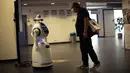 Seorang pria melihat pada robot yang dapat mendeteksi suhu dan masker di rumah sakit Universitas UZA di Antwerpen, Belgia pada 29 Mei 2020. Perusahaan Belgia, ZoraBots, menguji robot yang disebut CRUZR tersebut sebelum digunakan dalam beberapa minggu mendatang. (AP/Francisco Seco)