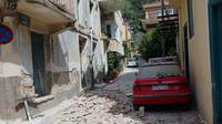 Puing-puing bangunan berserakan menutupi jalan akibat gempa bumi berukuran 6,3 SR di Pulau Lesbos, Yunani Timur, Senin (12/6). Para petugas penyelamat masih sibuk mencari korban di tengah reruntuhan rumah dan bangunan. (STRINGER / AFP)