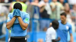 Striker Uruguay, Luis Suarez bersedih sambil menutupi wajah dengan jersey setelah kalah atas Prancis pada perempat final Piala Dunia 2018 di Nizhny Novgorod Stadium, Jumat (6/7). Timnas Uruguay tersingkir usai ditumbangkan Prancis 0-2 . (AP/Hassan Ammar)