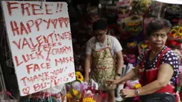 Toko bunga menawarkan pesona keberuntungan dan masker wajah gratis sebagai bagian dari promosi Hari Kasih Sayang di Alabang, Manila, Filipina (13/2/2020). (AP Photo/Aaron Favila)