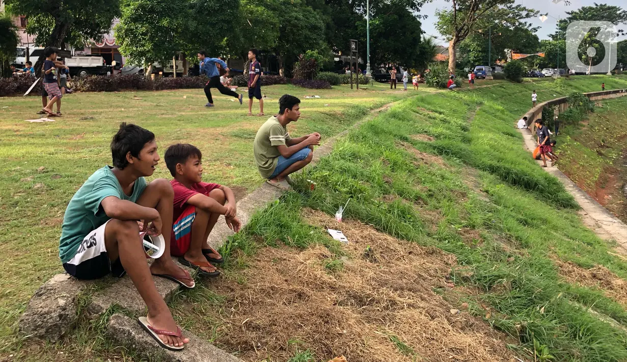 Anak-anak bermain di sekitar bantaran Kanal Banjir Timur (KBT), kawasan Cipinang Muara, Jakarta, Selasa (16/6/2020). Sebagian besar warga masih mengabaikan protokol kesehatan dengan tidak menjaga jarak serta tanpa menggunakan masker. (Liputan6.com/Immanuel Antonius)