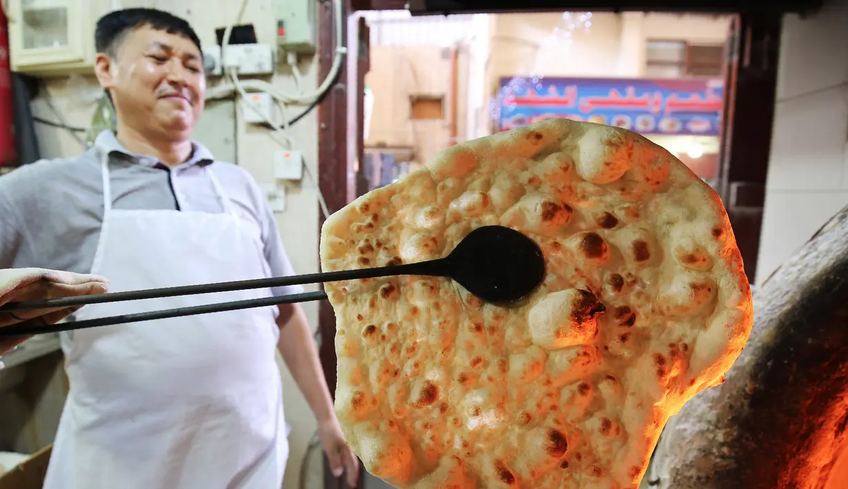 Tukang roti memanggang roti Iran atau taftoon di sebuah toko di Kuwait City, Kuwait, 27 Juni 2019. Taftoon telah menjadi makanan pokok di Kuwait selama beberapa dekade. (YASSER AL-ZAYYAT/AFP)