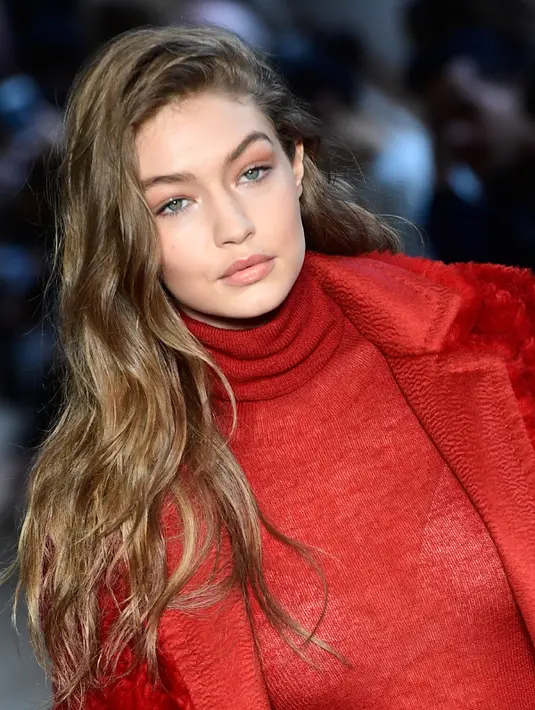 Ekspresi Gigi Hadid saat membawakan busana karya Max Mara selama Autumn / Winter 2017 di Milan Fashion Week, Italia (23/2). Gigi Hadid tampil cantik dan seksi dengan busana tipis berwarna merah. (AFP Photo / Miguel Medina)