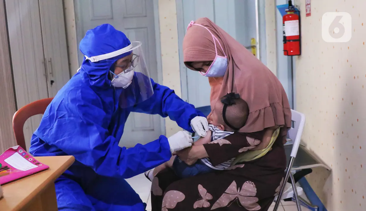 Bidan mengenakan alat pelindung diri (APD) saat melakukan imunisasi kepada bayi di Puskesmas Karawaci Baru, Tangerang, Banten, Rabu (13/5/2020). Pelayanan imunisai sesuai jadwal ini diberikan kepada bayi untuk menambah kekebalan imun tubuh. (Liputan6.com/Angga Yuniar)