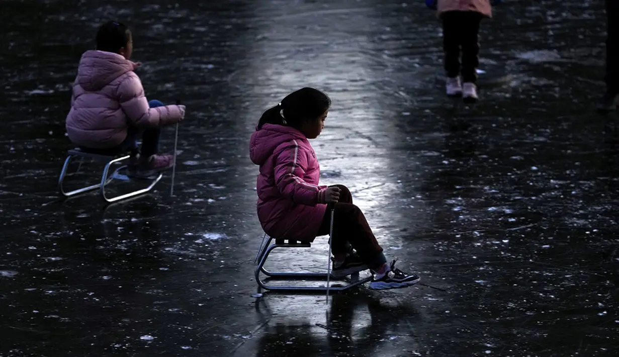 Anak-anak bermain ice skating di sungai yang membeku dekat pemukiman warga saat libur Tahun Baru di Beijing, China, 3 Januari 2022. (AP Photo/Andy Wong)