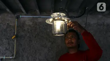 Pekerja menyalakan lampu menggunakan bahan bakar biogas yang mengubah kotoran sapi menjadi gas untuk kebutuhan tumah tangga di kawasan Pancoran, Jakarta, Selasa (12/12/2023). (Liputan6.com/Herman Zakharia)
