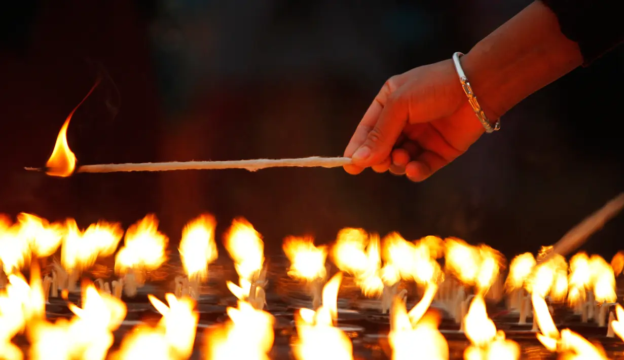 Seorang umat Buddha Nepal menyalakan lilin saat perayaan Buddha Jayanti atau Buddha purnima di stupa Boudhanath, Kathmandu, Nepal (30/4). (AP/Niranjan Shrestha)