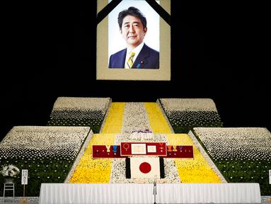 Potret mantan Perdana Menteri Jepang Shinzo Abe terlihat pada altar saat pemakaman kenegaraannya di Nippon Budokan, Tokyo, Jepang, 22 September 2022. Prosesi diawali dengan pemberian sambutan dari Wakil Ketua Panitia Pelayanan Pemakaman dan dilanjutkan dengan pengumandangan Lagu Kebangsaan Jepang. (Franck Robichon/Pool Photo via AP)