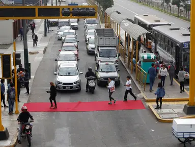 Sebum karpet merah terbentang di salah satu ruas jalan di distrik Magdalena del Mar, Lima, Peru, Sabtu (2/7). Aksi tersebut dilakukan untuk pejalan kaki agar bisa menyeberang dengan nyaman. (REUTERS / Guadalupe Pardo)