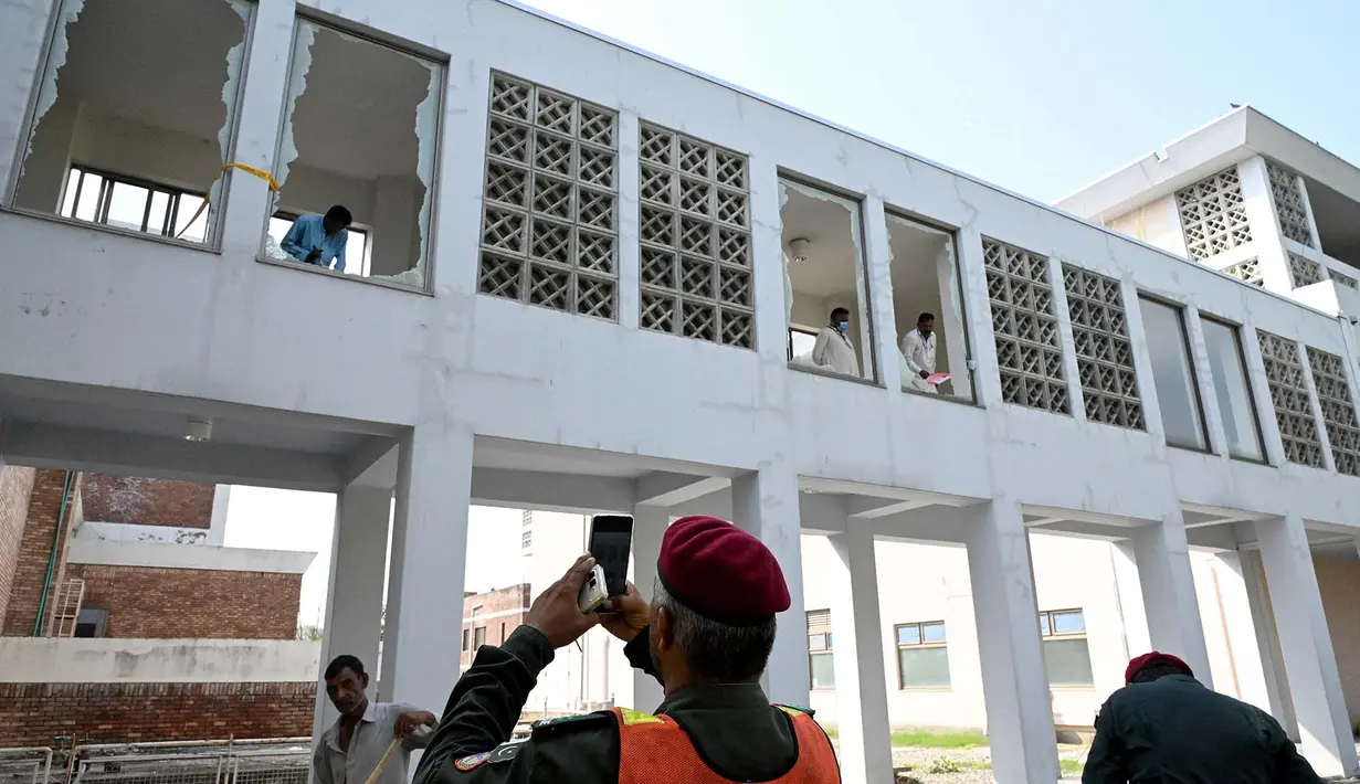 Para pekerja menyingkirkan pecahan kaca jendela setelah insiden kebakaran di luar bangsal Kesehatan Ibu dan Anak (MCH) di Rumah Sakit Pakistan Institute of Medical Sciences (PIMS), Islamabad, Pakistan, Rabu, 26 Agustus 2026. (AFP/  Aamir Qureshi)
