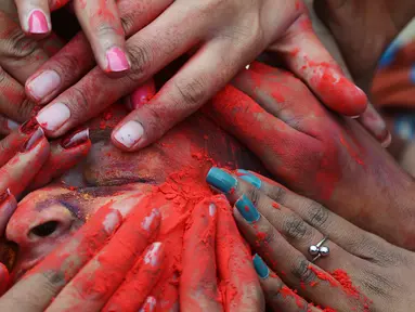 Wajah seorang siswa dilumurkan bubuk warna saat perayaan Holi di Kolkata, India (7/3). Holi atau Festival Warna adalah festival awal musim semi yang dirayakan di India, Nepal, Bangladesh, dan negara-negara yang mayoritas beragama Hindu. (AFP/Dibyangshu)