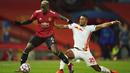 Gelandang Manchester United, Paul Pogba, berebut bola dengan pemain RB Leipzig, Benjamin Henrichs, pada laga Liga Champions di Stadion Old Trafford, Kamis (29/10/2020). MU menang dengan skor 5-0. (AP/Dave Thompson)