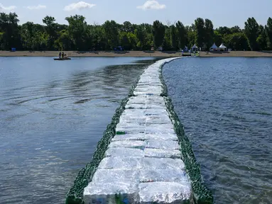 Warga memeriksa jembatan apung dari botol plastik yang ditempatkan di Danau Ada Ciganlija di Beograd, Serbia, Kamis, 27 Juli 2023. (AP Photo/Darko Vojinovic)
