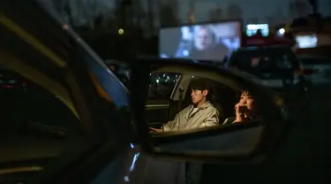 Sepasang suami istri duduk di mobil mereka ketika menonton pemutaran film di sebuah bioskop kendara atau drive-in cinema di Seoul, Korea Selatan, 21 Maret 2020. Jenis bioskop ini menjadi pilihan yang lebih bagi warga Seoul untuk menikmati film di tengah pandemi virus corona Covid-19. (Ed JONES/AFP)