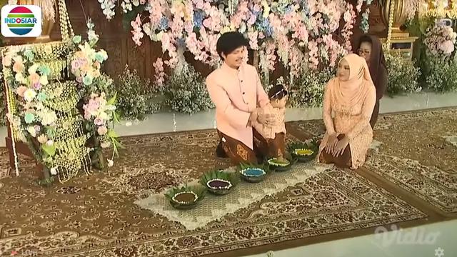 Atta Halilintar dan Aurel Hermansyah mendampingi putri mereka Ameena Hanna Nur Atta menjalani upacara Tedak Siten di acara 7 bulanan. (Foto: Indosiar/Vidio)
