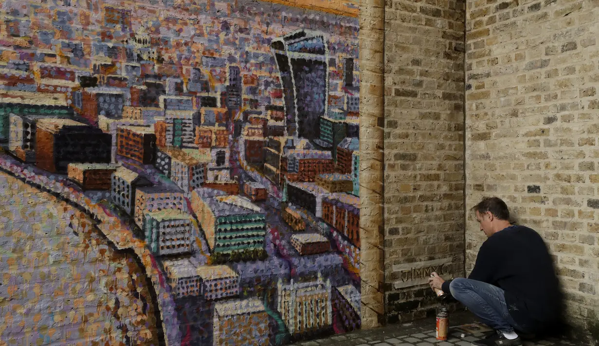 Seniman jalanan Australia James Cochran menandatangani mural lanskap kota London-nya saat ia menyelesaikan hanya dengan lapisan pernis yang tersisa untuk diselesaikan pada hari berikutnya, di dinding Network Rail oleh Blackfriars Station, di London (5/10/2020). (AP Photo/Matt Dunham)
