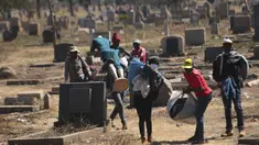 Pedagang Zimbabwe membawa dagangannya di kuburan setelah kabur dari kejaran polisi yang mengejar mereka setelah kedapatan berjualan dari tempat yang tidak ditentukan karena pembatasan COVID-19 di Harare, Kamis (29/7/2021). (AP Photo/Tsvangirayi Mukwazhi)