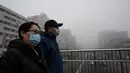 Orang-orang yang memakai masker melintasi jalan layang pada hari yang berkabut dan tercemar di Beijing, Sabtu (6/11/2021). Jalan raya dan taman bermain sekolah di Beijing ditutup pada Jumat (5/11) karena polusi kabut asap yang tebal, setelah China meningkatkan produksi batu bara. (JADE GAO/AFP)
