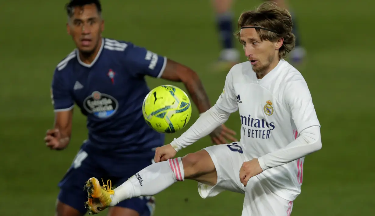 Gelandang Real Madrid, Luka Modric (kanan) mengontrol bola dari kawalan pemain Celta Vigo, Renato Tapia pada pertandingan lanjutan La Liga Spanyol di stadion Alfredo Di Stefano, Minggu (3/1/2021). Skuad asuhan Zidane ke puncak klasemen sementara dengan 36 poin dari 17 laga. (AP Photo/Manu Fernandez)