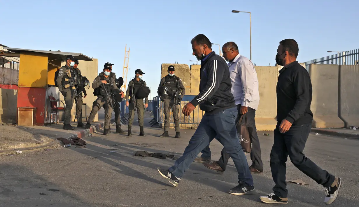 Anggota pasukan keamanan Israel berjaga-jaga di pos pemeriksaan Qalandia antara kota Ramallah Tepi Barat dan Yerusalem, ketika orang-orang Palestina menyeberang untuk menghadiri sholat Jumat kedua bulan Ramadhan di masjid Al-Aqsa, Jumat (23/4/2021). (ABBAS MOMANI / AFP)