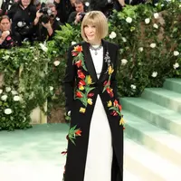 Anna Wintour tampil mengenakan gaun lengan panjang berbahan satin sutra berpotongan bias berwarna putih yang ditumpuk tuksedo berbahan wol dengan kerah selendang satin sutra dihiasi motif bunga menggunakan bulu yang diwarnai tangan, manik-manik berwarna, dan mutiara sulaman. [Foto: Instagram/wintourworld]