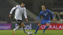 Gelandang Jerman, Kai Havertz membawa bola dari kawalan pemain Islaandia, Lucas Gudjohnsen dalam lanjutan laga kualifikasi grup J Piala Dunia 2022 di Reykjavik, Islandia, Kamis (9/9/2021). Kemenangan ini membuat Jeman nyaman di puncak klasemen Grup J dengan poin 15. (AP Photo/Arni Torfason)