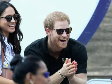 Putra kerajaan Inggris, Pangeran Harry dan aktris Meghan Markle menonton pertandingan tenis kursi roda selama Invictus Games 2017 di Toronto, Kanada, Senin (25/9). Ini merupakan penampilan publik pertama mereka bersama. (Chris Jackson/GETTY IMAGES/AFP)