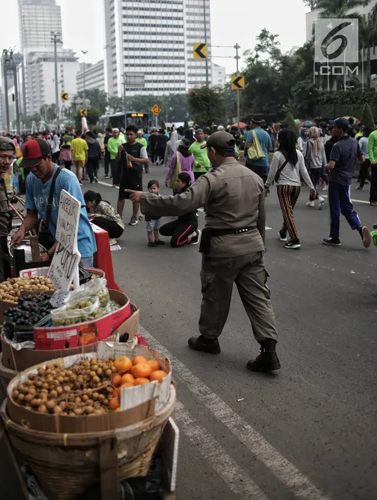 Satpol PP DKI Jakarta menertibkan PKL yang berdagang di kawasan Car Free Day, Bundaran HI, Jakarta, Minggu (20/1). Penertiban dilakukan karena telah membuat ketidaknyamanan bagi para pengunjung CFD yang ingin berolahraga. (Liputan6.com/Faizal Fanani)