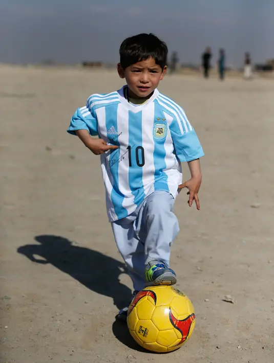Murtaza Ahmadi (5), bocah asal Afghanistan, berpose dengan memakai jersey yang ditandatangani oleh bintang Barcelona yang juga idolanya, Lionel Messi, sebelum bermain sepak bola di sebuah lapangan terbuka di Kabul, Jumat (26/2). (REUTERS/Omar Sobhani)