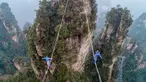 Dua kontestan berpakaian karakter Avatar berpacu sepanjang slackline di Pegunungan Huangshizhai di Zhangjiajie, Hunan, China, Minggu (23/12). Aksi tersebut dilakukan saat mengikuti slackline internasional.  (STR/AFP)