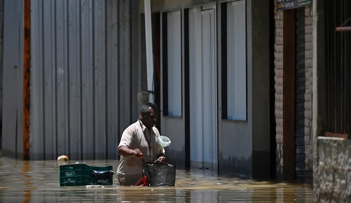 Seorang pria dengan sepedanya mengarungi air di jalanan yang tergenang banjir di komunitas Pilar di Duque de Caxias, Negara Bagian Rio de Janeiro, Brasil, pada 15 Januari 2024. (Mauro PIMENTEL/AFP)