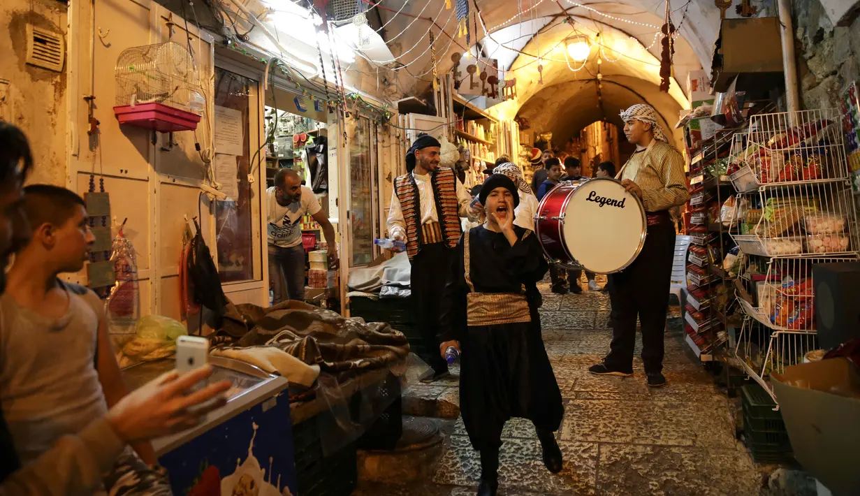 Kelompok pemuda Palestina memukul gendang ketika membangunkan kaum muslim untuk sahur di Kota Tua Yerusalem, Selasa (5/6). Pekerjaan ini dilakukan sukarela meski ada sebagian orang memberikan upah sebagai balas jasa. (AP/Mahmoud Illean)