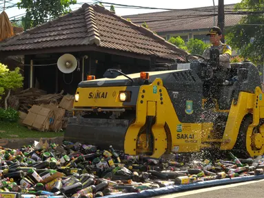 Polisi menggunakan alat berat saat memusnahkan ribuan botor miras di Polres Kota Tangerang Banten, Rabu, (23/12).Polresta Tangerang memusnahkan miras sebanyak 11.155 botol dan 264 Ciu yang berkemas botol mineral. (Liputan6.com/Faisal R Syam)