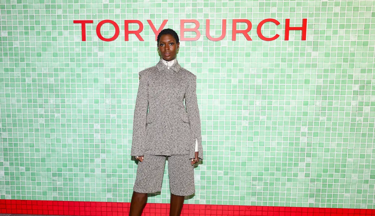 Jodie Tuner-Smith tampil mengenakan koleksi Resort 2025 Look 9, Squared Shoulder Field Jacket dan Shorts, Cotton Striped Shirt, the Pierced XL Pump, Lee Radziwill Double Bag, serta Miller Oval Sunglasses.  [Dok/Tory Burch].