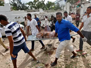Sejumlah pria membawa jenazah korban serangan bom yang terjadi di sebuah restoran di Mogadishu, Somalia, Kamis (15/6). (AP Photo)
