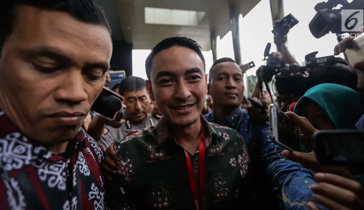 Gubernur Jambi Zumi Zola dikawal pria berseragam batik meninggalkan Gedung KPK seusai menjalani pemeriksa, Jakarta, Jumat (5/1). Zumi hanya memberikan senyuman saat dikerubungi awak media yang mengajukan pertanyaan. (Liputan6.com/Faizal Fanani)