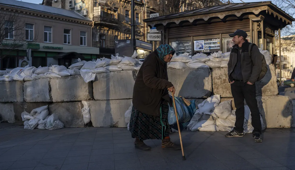 Seorang wanita lanjut usia berjalan melewati balok beton dengan karung pasir di sebuah jalan di Odesa, Ukraina selatan, pada Selasa, 22 Maret 2022. Perang Rusia yang tak henti-hentinya di Ukraina memaksa lebih banyak pengungsi untuk meninggalkan rumah mereka. (AP Photo/Petros Giannacouris)