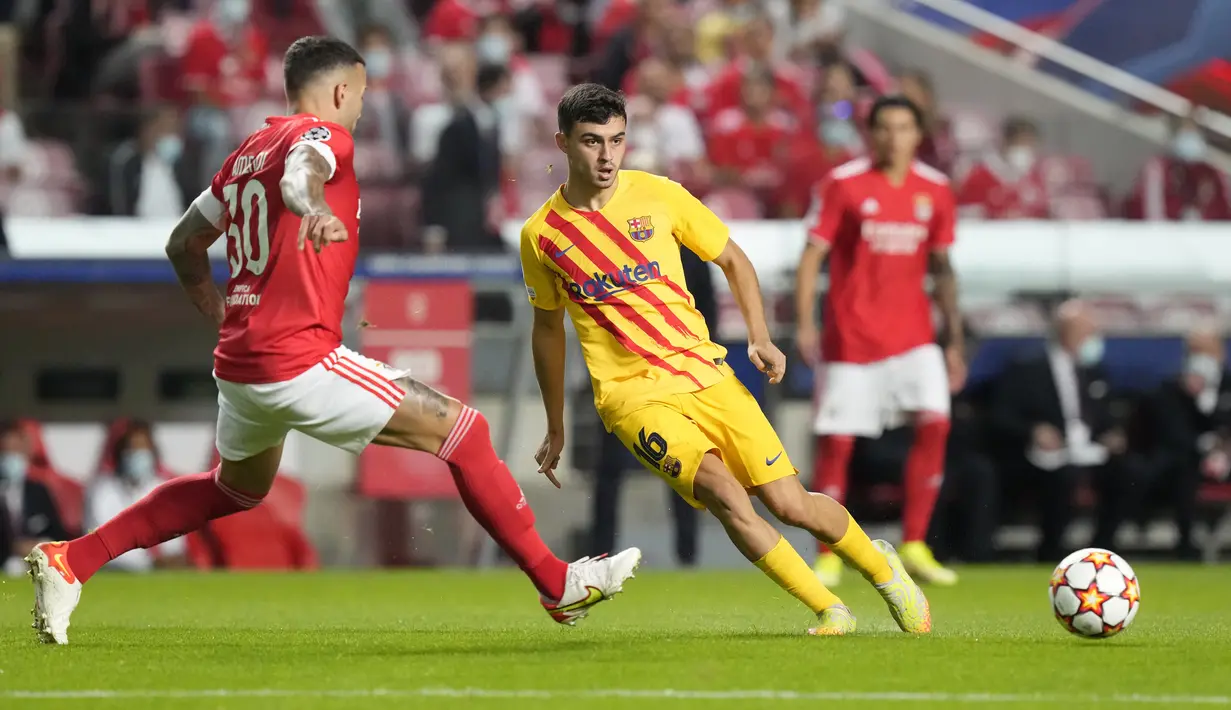 Gelandang Barcelona, Pedri mengumpan bola dari kawalan pemain Benfica, Nicolas Otamendi pada pertandingan grup E Liga Champions di stadion Luz di Lisbon, Portugal, Kamis (30/9/2021). Kemenanga atas Barcelona membuat Benfica berada di posisi kedua klasemen. (AP Photo/Armando Franca )