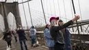 Turis mengambil foto di Jembatan Brooklyn, AS, Rabu (1/3). Menurut NYC & Co, larangan perjalanan yang sempat diucapkan Presiden Donald Trump telah menghambat minat pariwisata internasional. (Drew Angerer / Getty Images / AFP)