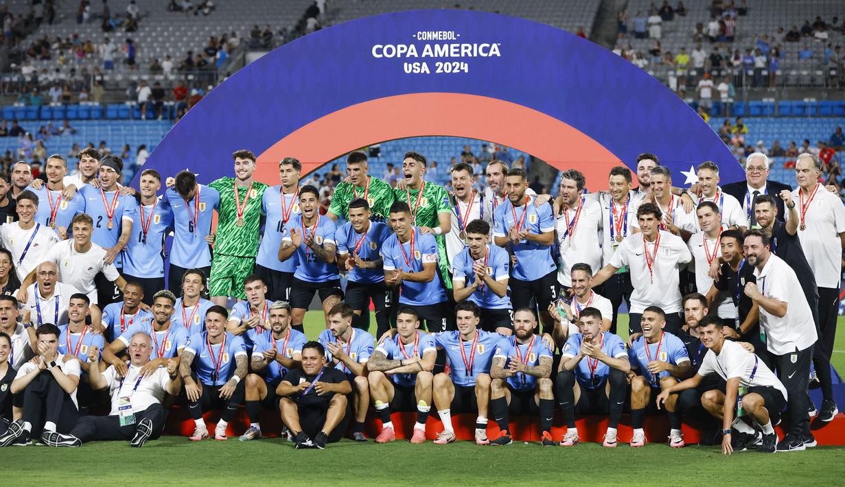 Para pemain Timnas Uruguay berfoto bersama di atas podium merayakan keberhasilan merebut posisi ketiga Copa America 2024 usai mengalahkan Timnas Kanada lewat babak adu penalti di Bank of America Stadium, Charlotte, Amerika Serikat, Minggu (14/7/2024) pagi WIB. (AP Photo/Nell Redmond)