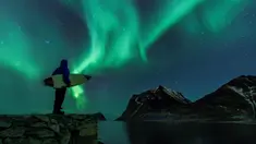 Seorang surfer melihat Cahaya Utara atau aurora borealis di Utakleiv, Norwegia utara (9/3). Aurora ini adalah sebuah peristiwa langit yang cantik berupa pancaran cahaya yang menyala-nyala di atmosfer sekitar lingkaran Arktik. (AFP/Olivier Morin)
