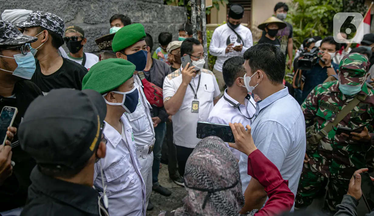 Anggota FPI mengadang anggota Polda Metro Jaya yang ingin memberi surat pemanggilan kepada Rizieq Shihab di kediamannya di Petamburan, Jakarta, Rabu (2/12/2020). Polisi kembali memanggil Rizieq Shihab terkait acara Maulid Nabi dan resepsi putrinya. (Liputan6.com/Faizal Fanani)