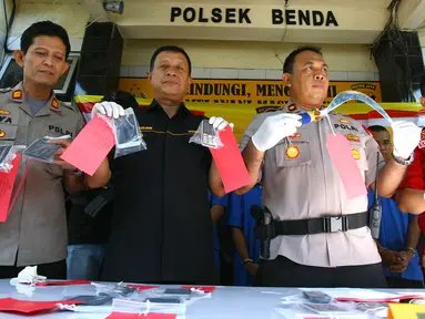 Polisi menunjukkan barang bukti celurit dan handphone di Mapolsek Benda, Tangerang, Banten, Senin (19/11). Polisi menangkap otak pelaku kejahatan spesialis handphone dan tiga tersangka lainnya. (Liputan6.com/Fery Pradolo)