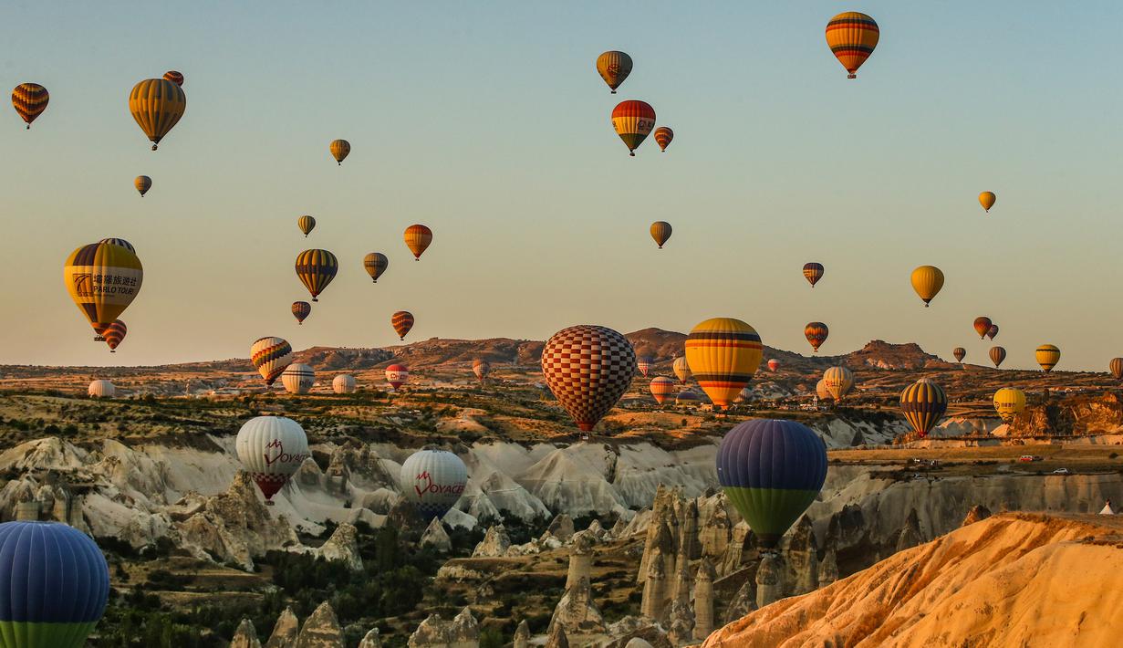 Balon udara membawa wisatawan naik ke langit saat matahari terbit di Kapadokia, Turki, Selasa (7/8). Kapadokia memiliki sejumlah keajaiban alam, khususnya Cerobong Peri (Fairy Chimney). (AP Photo/Emrah Gurel)