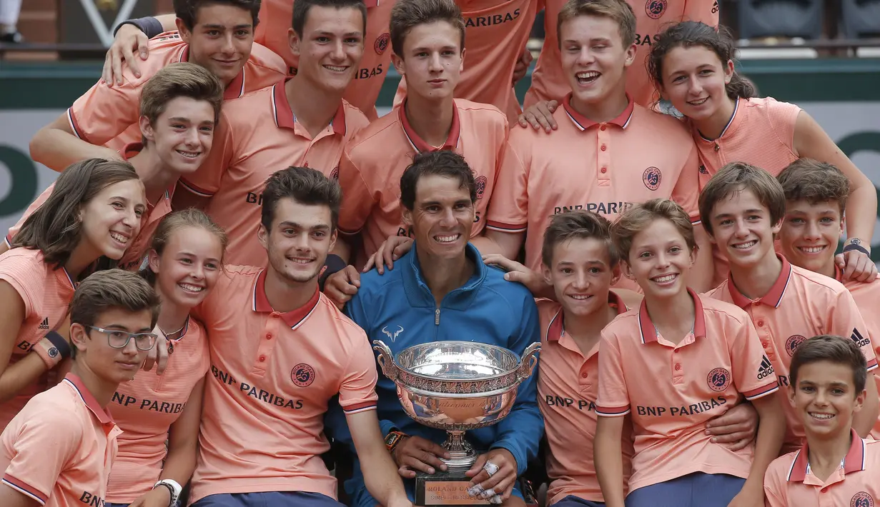 Ball girls dan ball boy melakukan foto bersama dengan Rafael Nada usai meraih trofi Prancis Terbuka 2018 di Roland Garros stadium, Paris, (10/6/2018). Nadal menang atas Dominic Thiem tiga set 6-4, 6-3, 6-2. (AP /Michel Euler)