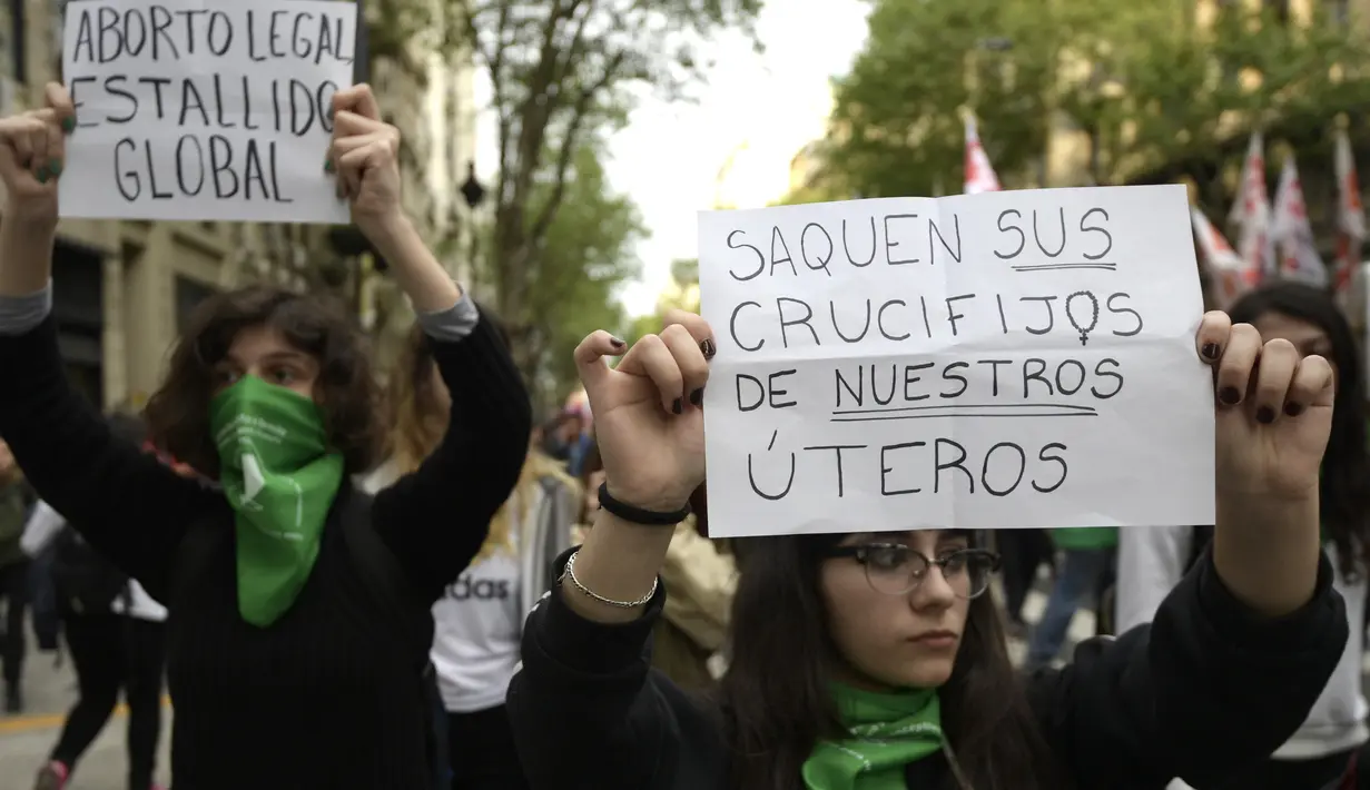 Dua orang demonstran menunjukan poster saat menggelar aksi di Buenos Aires, Argentina (29/9). Dalam aksi ini mereka meminta dekriminalisasi aborsi, atau meminta perbuatan aborsi bukan lagi menjadi pelanggaran hukum. (AFP Photo/Juan Mabromata)